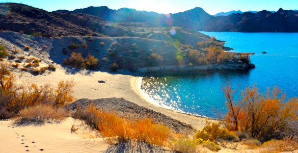 Picture of a beach on a desert lake with mountains in the background during sunset.