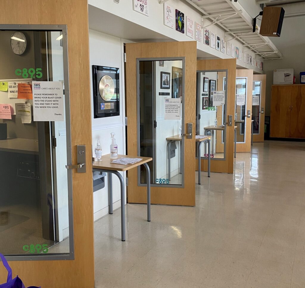 a photo of 5 windowed doors along a hallway. Next to the nearest door is a platinum record in a glass picture frame.