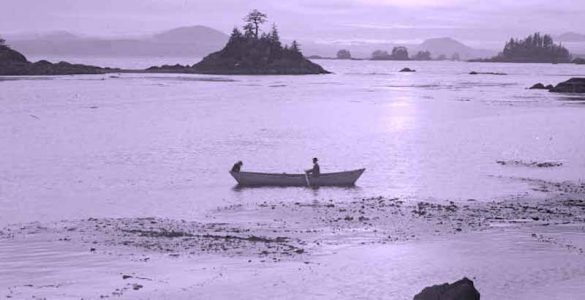 Old black and white photograph of a person in a canoe in Alaskan waters.