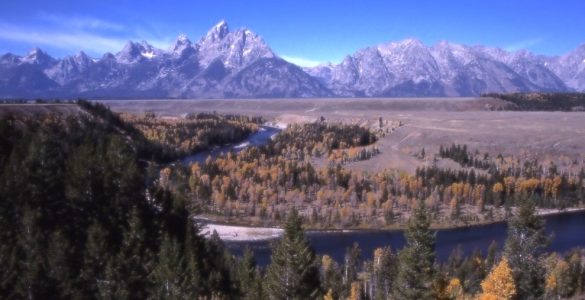 An autumn landscape with mountains and a winding river.