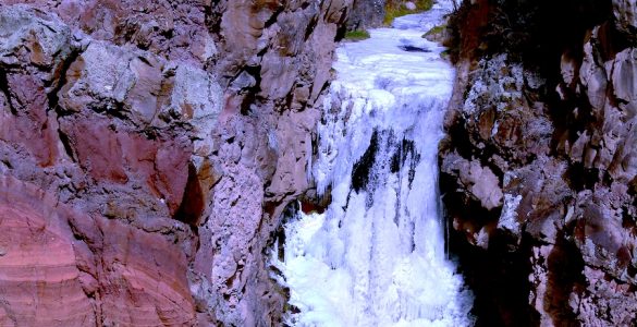 A mountain waterfall with a steep drop, fully frozen.