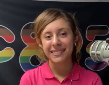 A photo of a young woman's face. She has auburn hair, tan skin, and is smiling broadly.