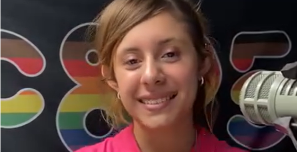 A photo of a young woman's face. She has auburn hair, tan skin, and is smiling broadly.