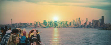 Sunset over Seattle skyline viewed from a waterfront with a group of people in the foreground enjoying the scene.