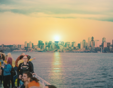 Sunset over Seattle skyline viewed from a waterfront with a group of people in the foreground enjoying the scene.