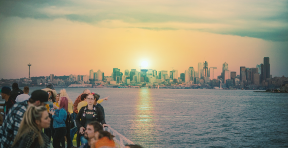 Sunset over Seattle skyline viewed from a waterfront with a group of people in the foreground enjoying the scene.