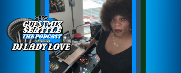 Woman standing at a DJ station with a microphone and laptop, displaying a music software interface. A large round logo with text: "Guest Mix Seattle The Podcast DJ Lady Love" overlays part of the image. There are framed pictures in the background and an interior setting is visible.
