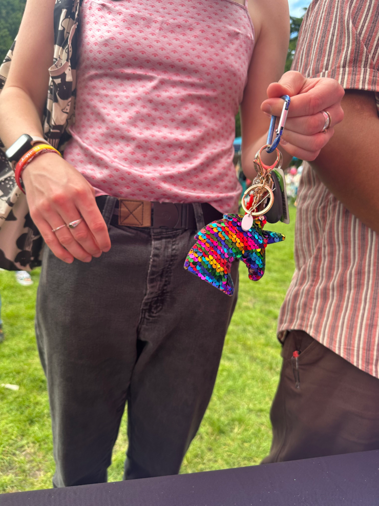 Two individuals exchanging colorful keychains outdoors at a community event.