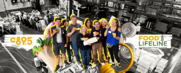 Group of volunteers at Food Lifeline, smiling and posing in a warehouse setting surrounded by boxes and canned goods, with a banner displaying gratitude and statistics about volunteer efforts.