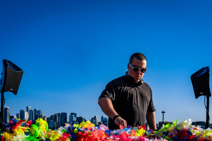 A DJ standing against a bright blue sky with the Space Needle in the background