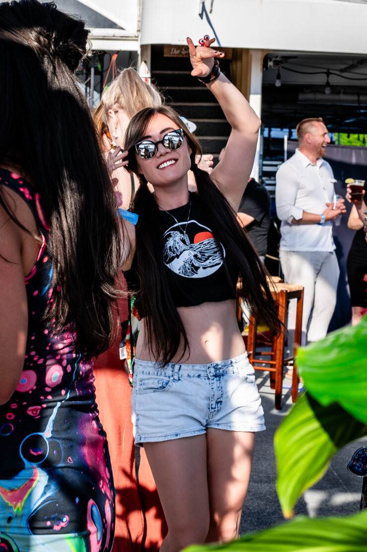 A young woman wearing sunglasses dancing in a crowd.