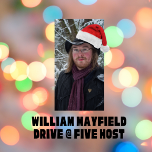 A young adult male with reddish hair and a moustache and beard in a snowy winterland setting with a cartoon Santa Hat on.