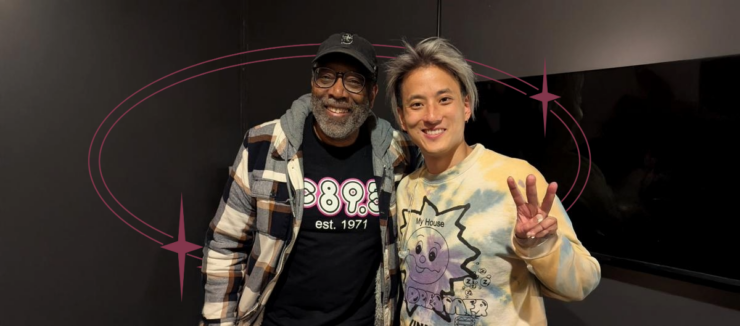 Two individuals posing for a photo in a room, one wearing a Disney-themed sweater and the other sporting a shirt with "895" printed on it.